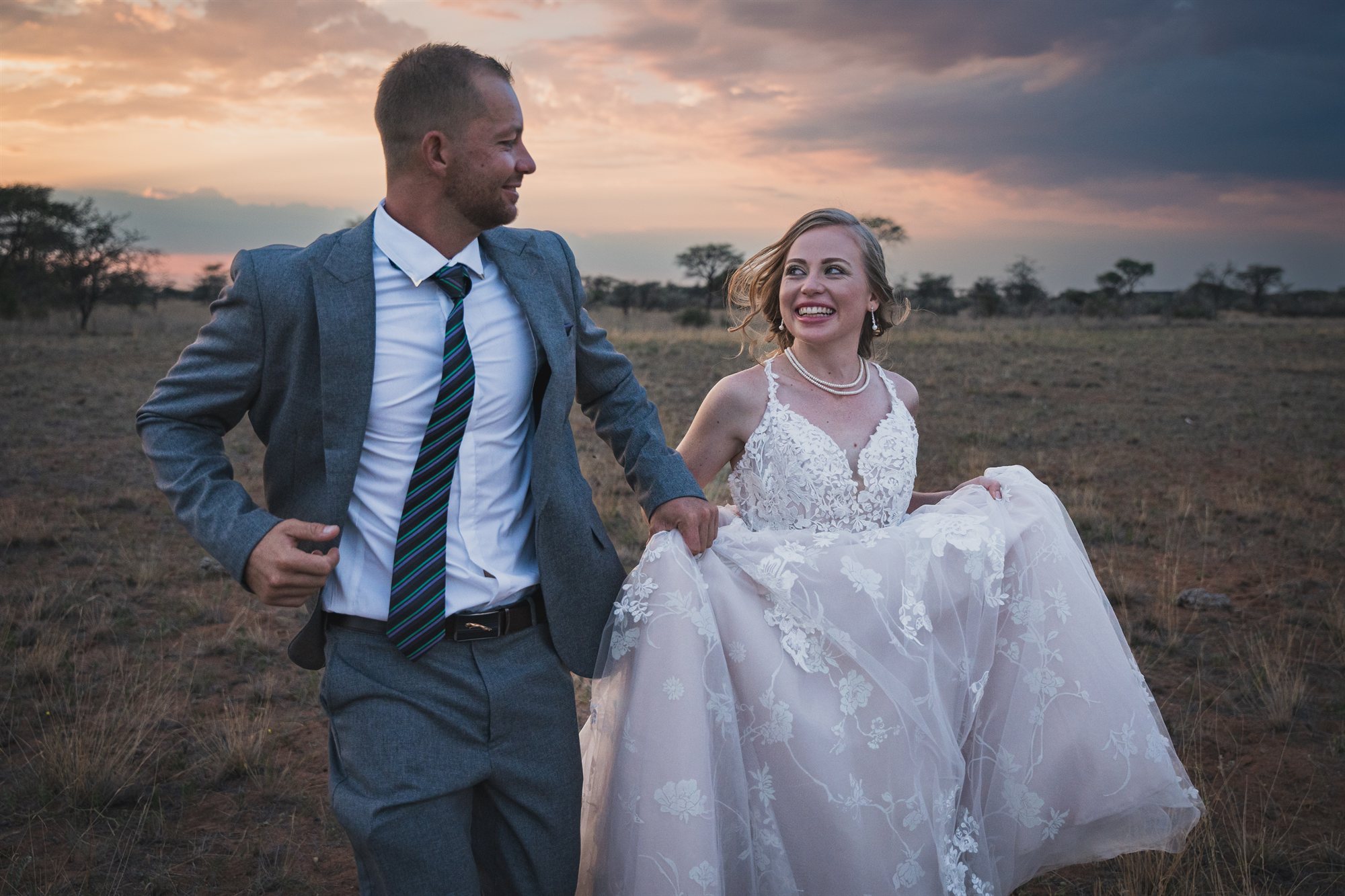 A couple walking through golden grass at sunset